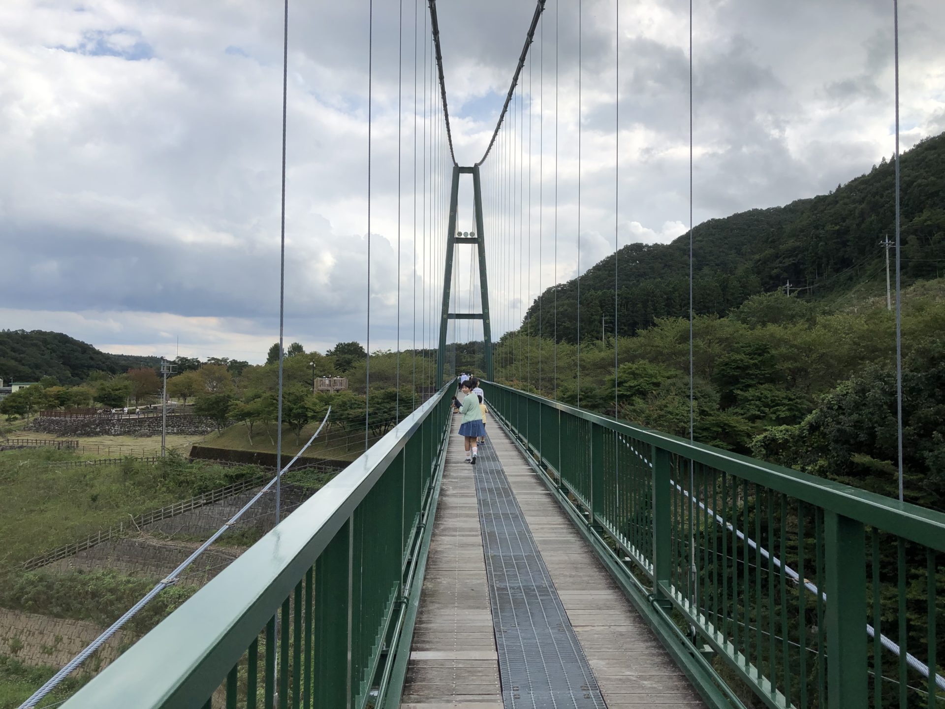 山あいに架かる長い吊り橋を、まっすぐ先へ見通した写真。
