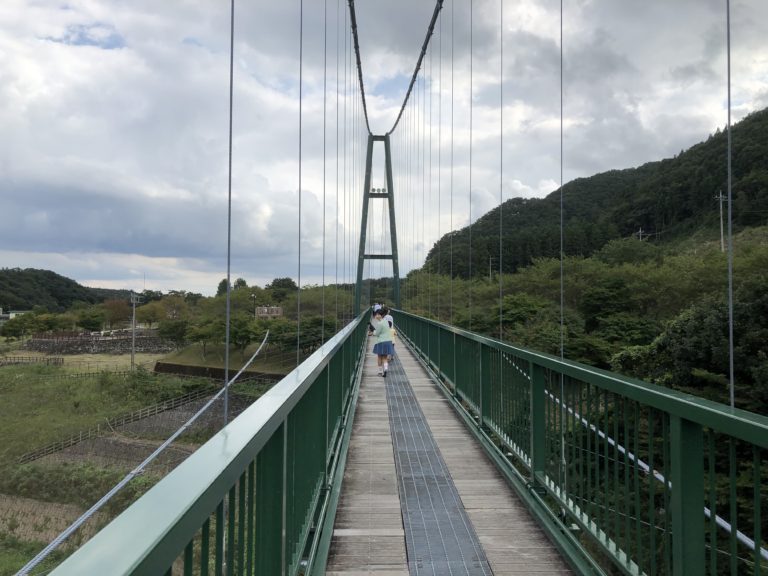 山あいに架かる長い吊り橋を、まっすぐ先へ見通した写真。